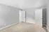 Bright empty bedroom with hardwood flooring and light gray walls.