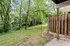 Charming backyard view with lush greenery and towering trees, featuring a rustic wooden fence.