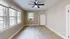 Inviting, sunlit room with large windows, modern light wood flooring, and a ceiling fan.