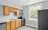 Spacious kitchen with wooden cabinets, stainless steel appliances, and large window providing natural light.