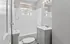 Elegant bathroom with white tiles, a bathtub, modern vanity, and natural light from a window.