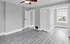 Bright room with sleek gray flooring, white doors, and a window with natural light.