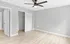 Inviting bedroom with light wood flooring, gray walls, a ceiling fan, and an open closet space.