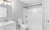 Bright bathroom with modern fixtures, featuring a sleek vanity, toilet, and full shower setup.