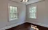 Charming room with two large windows and a ceiling fan, featuring natural light and hardwood floors.