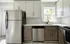 Renovated kitchen with stainless steel appliances, designer backsplash, and gold finishes on the cabinets and sink.