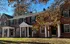 Beautiful row of classic red brick townhouses with white columns and black shutters, surrounded by autumn foliage.