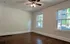 Inviting and spacious room with hardwood floors and large windows allowing natural light.