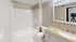 Modern bathroom with a granite countertop, white tile shower, and sleek lighting.