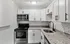 Modern kitchen with white cabinetry, granite countertops, and stainless steel appliances.