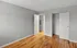 Bright empty bedroom with hardwood flooring and open closet space.