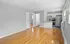 Modern open-concept apartment featuring polished hardwood floors, a sleek kitchen with stainless steel appliances, and ample natural light.