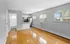 Bright, open-concept living area with gleaming hardwood floors, modern kitchen with stainless steel appliances, and ample natural light.
