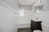 Bright, modern bathroom featuring elegant fixtures, a spacious vanity, and a full bathtub with sleek white tiles.