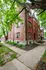 Charming red brick apartment building surrounded by lush green trees, creating a serene and inviting atmosphere.