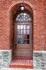 Charming brick entryway with arched doorway and vintage windows, exuding timeless architectural elegance.