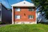 Charming brick apartment building with modern windows, set in a serene neighborhood with lush green lawns.