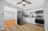 Modern kitchen with sleek stainless steel appliances, bright white cabinetry, and elegant hardwood floors opening into a spacious living area.