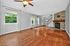 Inviting and spacious living room with elegant wooden flooring, stylish stone fireplace, and ample natural light through large windows.