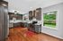 Charming kitchen featuring modern dark wood cabinetry, stainless steel appliances, and picturesque views of lush greenery.