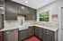Modern kitchen with sleek dark cabinetry, spacious countertops, and a large window offering lush garden views.