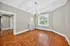 Elegant dining room with hardwood floors and large window offering natural light, complemented by a modern chandelier and neutral wall tones.