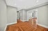 Bright and spacious hallway featuring elegant hardwood floors and modern recessed lighting, leading to an open living area with abundant natural light.