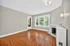 Inviting living room with elegant hardwood floors, abundant natural light from large windows, and a charming decorative fireplace.
