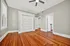 Bright room with elegant hardwood floors, modern ceiling fan, and crisp white closet doors, perfect for maximizing space and style.