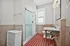 Bright and inviting bathroom featuring elegant red checkered flooring, a modern glass shower, and a sleek marble vanity.