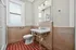 Charming bathroom with vintage red tile flooring, elegant marble sink, and bright natural lighting from a large window.
