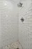 Modern shower with sleek white subway tiles and elegant hexagonal floor design.