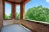 Charming brick balcony with expansive windows overlooking lush green trees, ideal for tranquil relaxation.