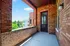 Charming brick balcony with a scenic view of lush greenery and neighboring buildings, perfect for enjoying the outdoors.