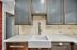 Modern kitchen with sleek dark cabinets, elegant backsplash, and a deep farmhouse sink for stylish functionality.