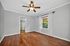 Bright and inviting bedroom with elegant ceiling fan, hardwood floors, and a view of lush greenery through the window.