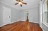 Bright, inviting room with hardwood floors and large windows, featuring a ceiling fan and access to a cozy walk-in closet.