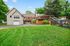 Charming country home with spacious backyard, showcasing a mix of brick and siding exterior, an inviting patio, and lush greenery.