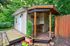 Charming backyard shed with a rustic wooden deck surrounded by lush greenery, perfect for gardening enthusiasts.
