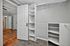 Spacious walk-in closet with elegant white shelving and ample storage space, adjacent to a room with warm hardwood flooring.