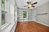 Bright room with elegant hardwood floors, built-in shelves, and large windows offering a serene garden view.