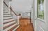 Charming entryway with elegant staircase and spacious living room featuring beautiful hardwood floors and a ceiling fan, perfect for comfortable living.