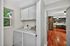 Bright laundry area with modern appliances adjacent to a spacious kitchen with elegant wood flooring.
