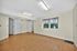 Spacious, bright room with elegant wood flooring, large window with floral curtains, and multiple doorways for easy access.