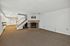 Spacious basement with cozy fireplace, featuring elegant carpet flooring and sleek built-in shelves. Bright lighting enhances the inviting atmosphere.