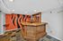 Chic basement bar area with distinctive orange and black wall art and a polished wooden counter, perfect for entertaining.