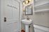 Charming bathroom featuring a contemporary pedestal sink, elegant fixtures, and a stylish wall mirror with warm lighting.