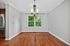 Charming dining area with elegant chandelier, hardwood floors, and a bright, leafy view through the large window.