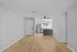 Bright and modern open-concept living area with stylish light wood flooring, stainless steel appliances, and a sleek ceiling fan, perfect for contemporary living.