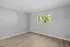 Bright and airy room with sleek laminated flooring and a large window offering a tranquil garden view.